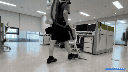 Breva Clean 작업자가 책상과 의자 사이 바닥을 청소기로 청소하는 모습